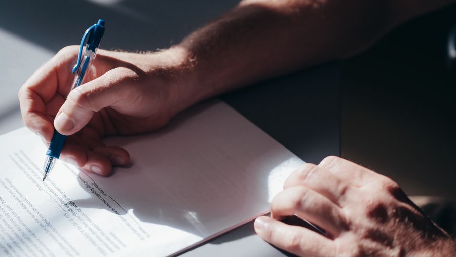 hand holding pen over paper